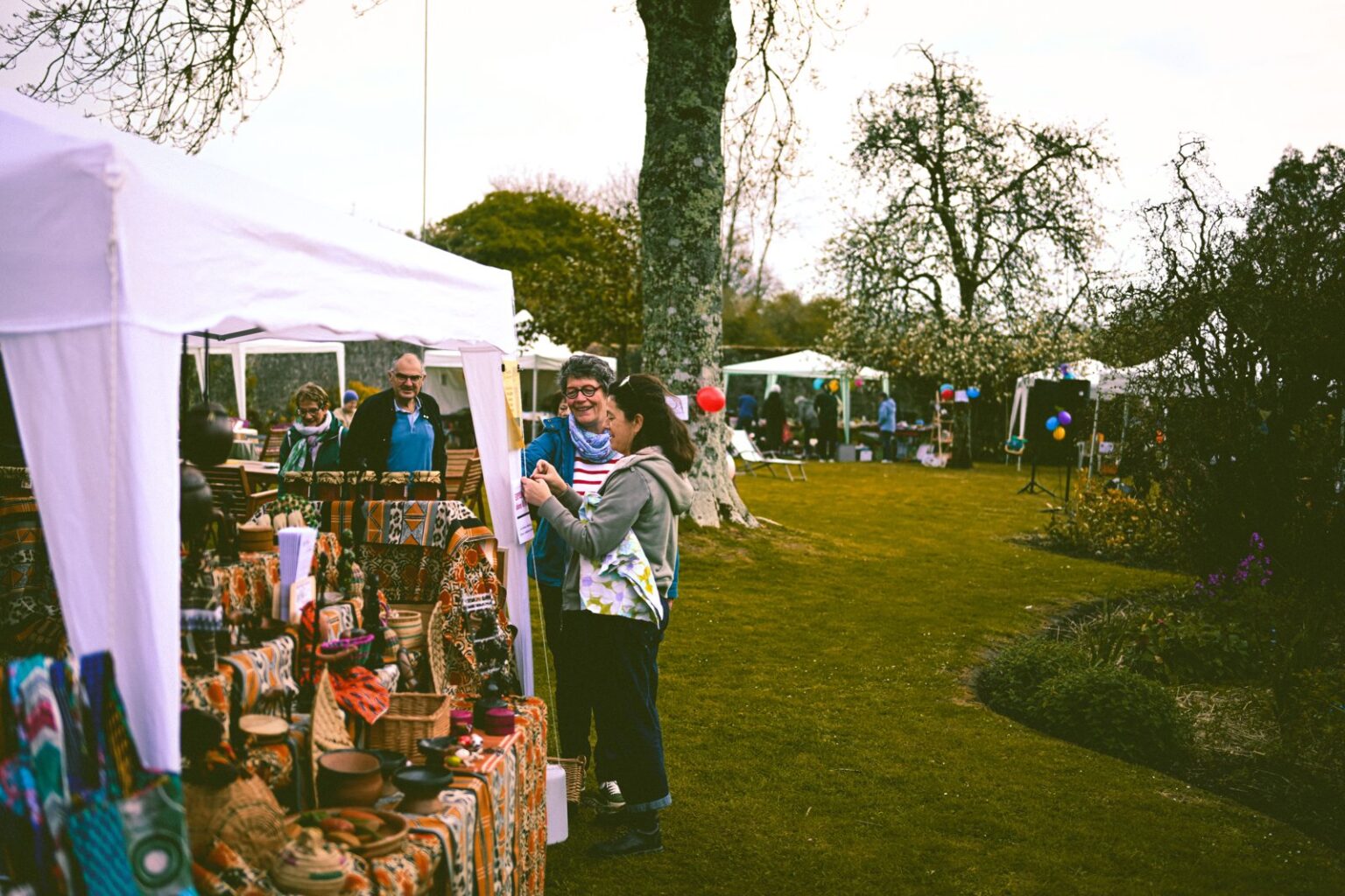 Outdoor community market with stalls and tents in a park